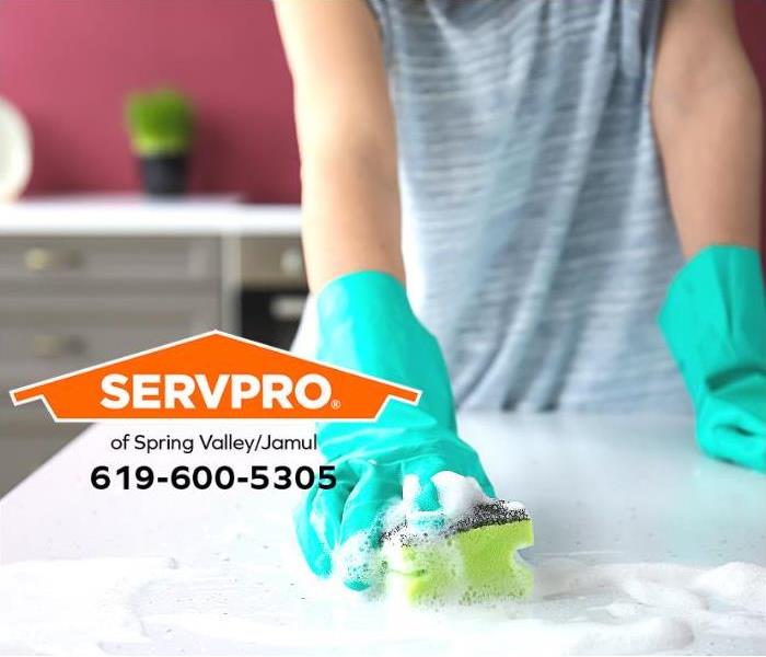 A hand is cleaning the surface of a table inside a house.