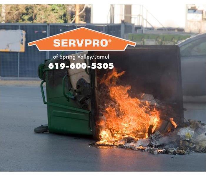 A green dumpster is on fire.