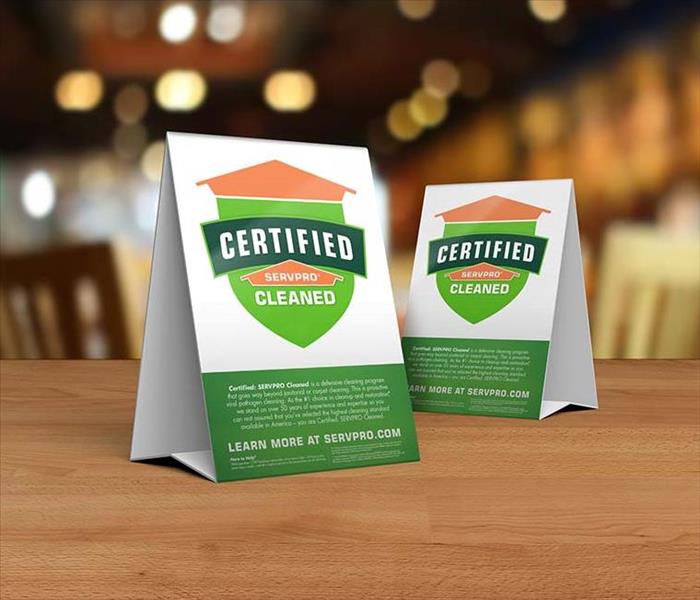 Table tent signs describing the Certified: SERVPRO Cleaned program on top of a wooden table